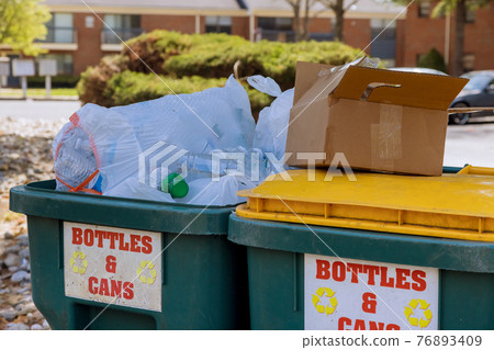Garbage containers near apartment building in district garbage bins to help separate recycle 76893409