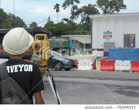MALACCA, MALAYSIA -APRIL 21, 2016: Surveyor with survey equipment at the construction site. He using this equipment to determine and check level.    76894035