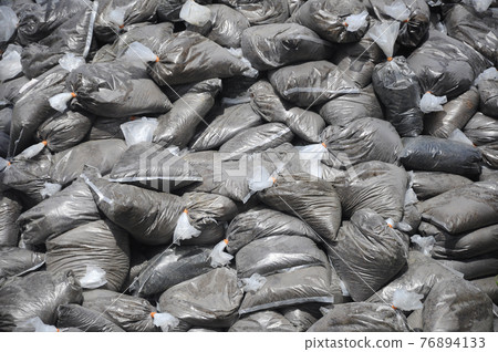 Dump the tree fertilizer which has been mixed with soil and packaged in plastic containers. 76894133