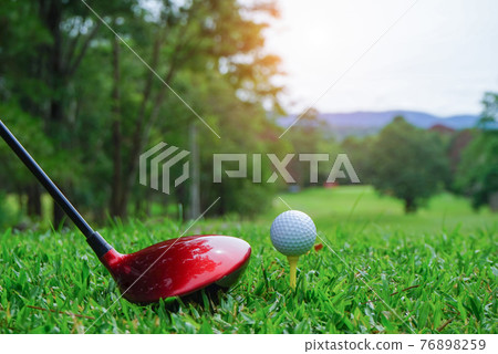 Golf balls and golf clubs on a green lawn in a beautiful golf course with morning sunshine. 76898259