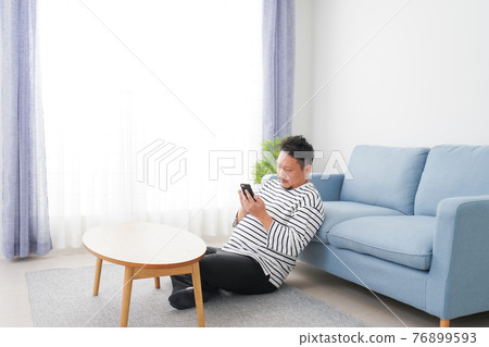 A man using a smartphone in the room A man using a smartphone in the room 76899593