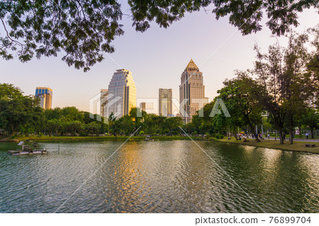 Lumpini park business district Bangkok cityscape from park with sunset sky Lumpini park business district Bangkok cityscape from park with sunset sky 76899704