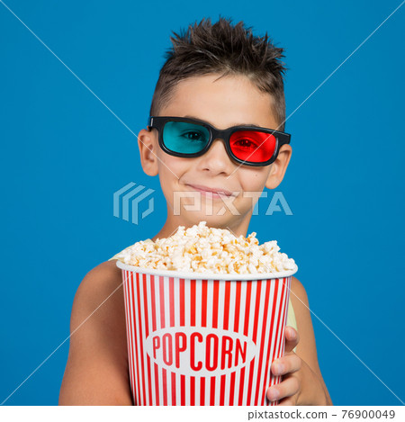 boy smiling in 3d glasses, with a bucket of popcorn, concept of cinema and entertainment boy smiling in 3d glasses, with a bucket of popcorn, concept of cinema and entertainment 76900049