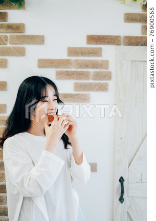 Young woman eating cookies 76900568