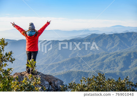 Woman traveler on peak of mountain 76901048