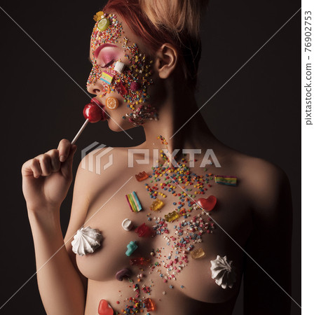 Naked woman in sweet candies licking lollipop Naked woman in sweet candies licking lollipop 76902753