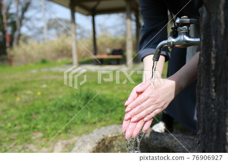 一個女人在溫暖的春日在公園散步時洗手 76906927
