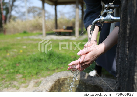 一個女人在溫暖的春日在公園散步時洗手 76906928