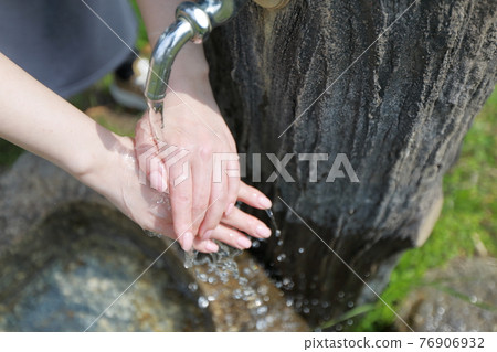 A woman washing her hands during a walk in a park on a warm spring day A woman washing her hands during a walk in a park on a warm spring day 76906932