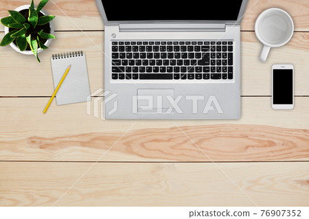 Home interior. Top view of wooden desk with laptop, cell phone, blank notebook for text and pencil, empty white mug and green flower. Desktop of business person working at home cozy interior Home interior. Top view of wooden desk with laptop, cell phone, blank notebook for text and pencil, empty white mug and green flower. Desktop of business person working at home cozy interior 76907352
