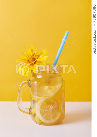 Fresh drink with lemon, glass decorated with yellow flower, summer lemonade with lemon slices and drinking straw, summer non alcoholic cocktail or iced tea for refreshing. Fresh drink with lemon, glass decorated with yellow flower, summer lemonade with lemon slices and drinking straw, summer non alcoholic cocktail or iced tea for refreshing. 76907390