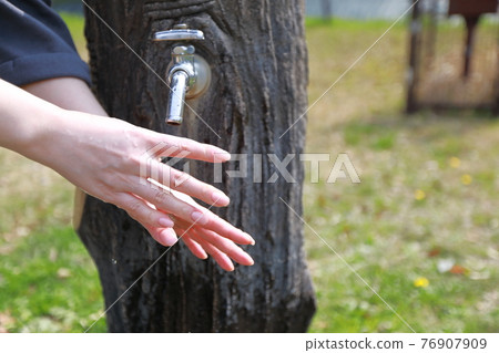 A woman washing her hands during a walk in a park on a warm spring day A woman washing her hands during a walk in a park on a warm spring day 76907909