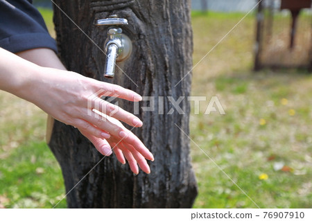 A woman washing her hands during a walk in a park on a warm spring day A woman washing her hands during a walk in a park on a warm spring day 76907910
