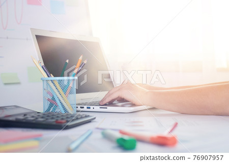 Indoor picture of person working on laptop, having calculator, pencils on table, comfortable working zone, being busy, well lighted room, using modern technologies during work. Technologies concept. Indoor picture of person working on laptop, having calculator, pencils on table, comfortable working zone, being busy, well lighted room, using modern technologies during work. Technologies concept. 76907957