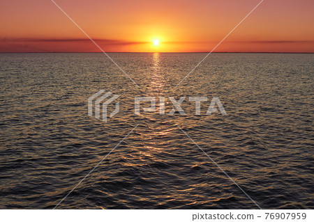 Deep sunset over calm smooth sea with bright colors and plenty of copy space. Beautiful natural summer seascape. Image of sunset with yellow red gradient colors. Horizontal photo. Red purple sunset 76907959