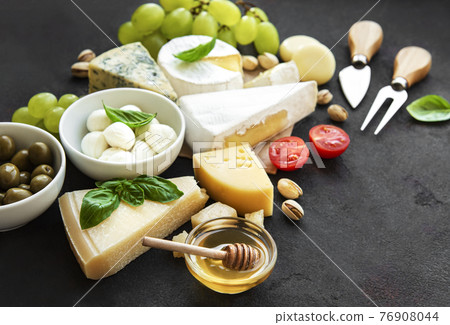 Various types of cheese, grapes, honey and snacks 76908044