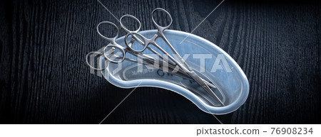 Hemostatic Forceps scissors put inside the plastic equipment holder on a wooden table top, overhead view photograph. 76908234