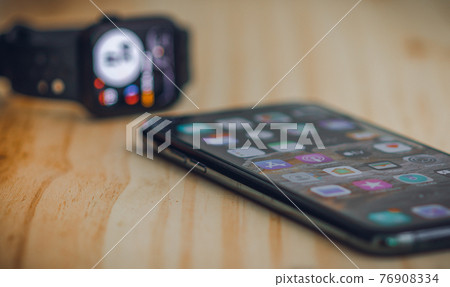 Galle, Sri Lanka - 02 19 2021: Apple iPhone 11 pro max and apple watch series 6 lay next to each on a wooden table, luxury, and lifestyle concept. low angle side view photograph. Galle, Sri Lanka - 02 19 2021: Apple iPhone 11 pro max and apple watch series 6 lay next to each on a wooden table, luxury, and lifestyle concept. low angle side view photograph. 76908334
