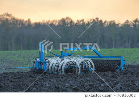 Blue plow in a field in the evening. Blue plow in a field in the evening. 76910308