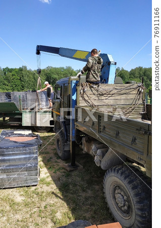 Unloading the front brick using a mobile crane in the village in private territory. Unloading the front brick using a mobile crane in the village in private territory. 76911166