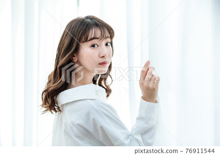 拉開窗簾沐浴陽光的年輕女子 拉開窗簾沐浴陽光的年輕女子 76911544