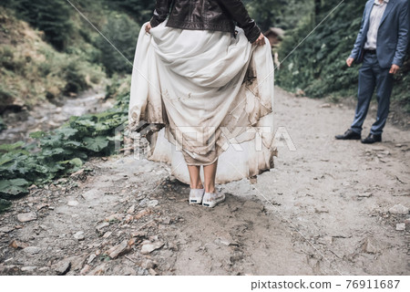 Wedding white dress of the bride dirty in the swamp 76911687