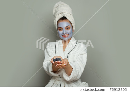 Smiling spa woman in blue cosmetic face mask  76912803
