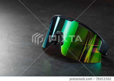 Green sports glasses with a mirror lens on a dark background Green sports glasses with a mirror lens on a dark background 76913302