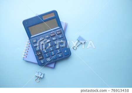 Close up of blue calculator and notepad on color background  76913438