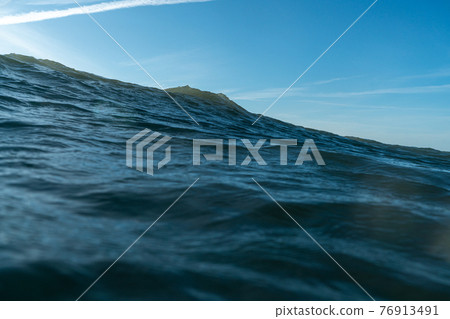 Breaking Waves and spray, white water and light reflected on the surface of the water 76913491