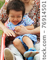 A 3-year-old boy playing with his grandma on a park slide 76914501