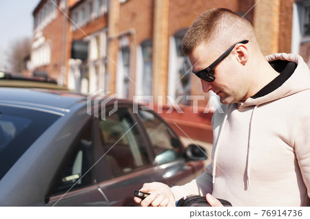 A young man next to his car on a sunny day on the street of the old city. 76914736