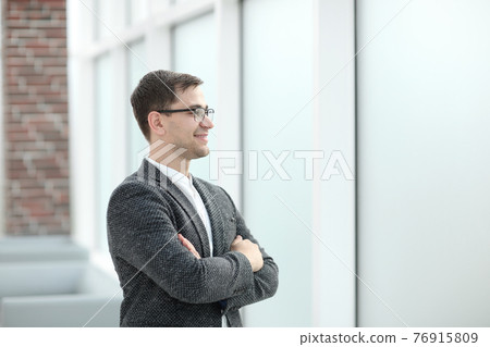 smiling business man looking through office window 76915809