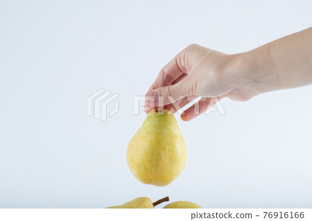 Female hand holding pear on white background Female hand holding pear on white background 76916166