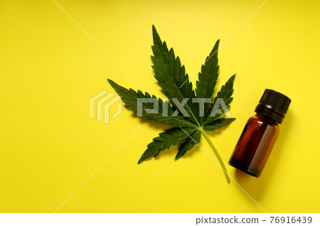 Medicinal cannabis leaf with marijuana oil in bottle on bright yellow background Medicinal cannabis leaf with marijuana oil in bottle on bright yellow background 76916439