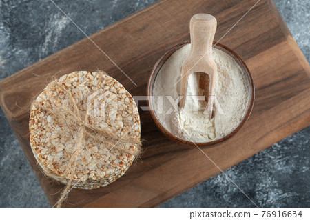 Stack of rice cakes and bowl of flour on wooden board Stack of rice cakes and bowl of flour on wooden board 76916634