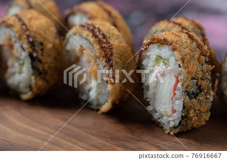 Hot sushi rolls with cream cheese on a wooden board Hot sushi rolls with cream cheese on a wooden board 76916667