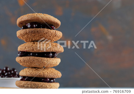 Crispy oatmeal cookies with blackcurrant berry confiture on it Crispy oatmeal cookies with blackcurrant berry confiture on it 76916709
