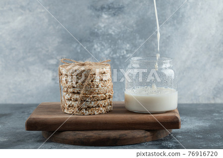 Glass of milk with delicious crispbread on wooden board Glass of milk with delicious crispbread on wooden board 76916720