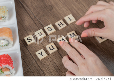 Yummy sushi writing on a wooden deck around sushi rolls Yummy sushi writing on a wooden deck around sushi rolls 76916731