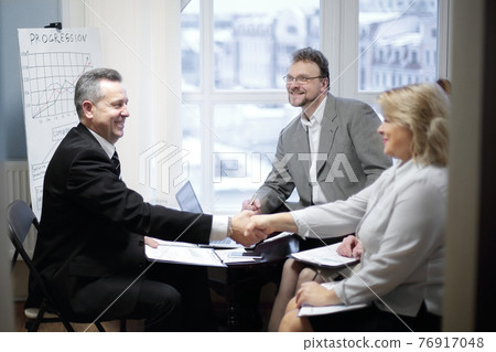 handshake of a businessman and business woman at a meeting handshake of a businessman and business woman at a meeting 76917048