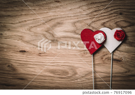 red and white heart on a stick on a wooden background. 76917096