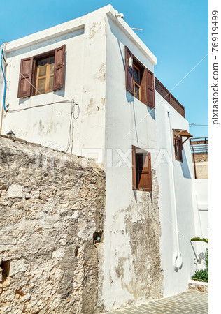 Narrow street with houses whitewashed walls and wooden shutters on windows Narrow street with houses whitewashed walls and wooden shutters on windows 76919499