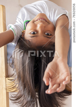A girl is upside down looking down from the top of her bunk A girl is upside down looking down from the top of her bunk 76920056