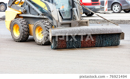 A small grader with a trailed nylon brush with hydraulics cleans the repaired section of the road from dirt. 76921494