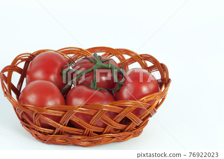 branch of ripe tomatoes in a wicker basket.isolated on white 76922023
