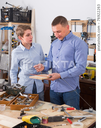 adult father teaching son сarpentry in the garage 76922263