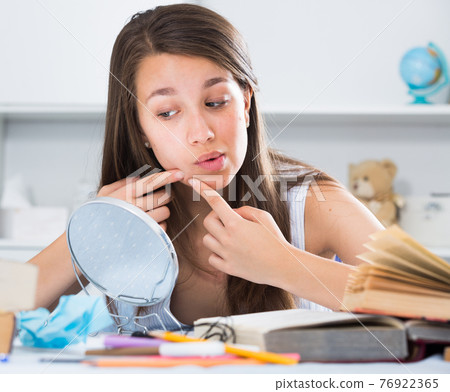 Girl is squeezing out a pimple before makeup making Girl is squeezing out a pimple before makeup making 76922365