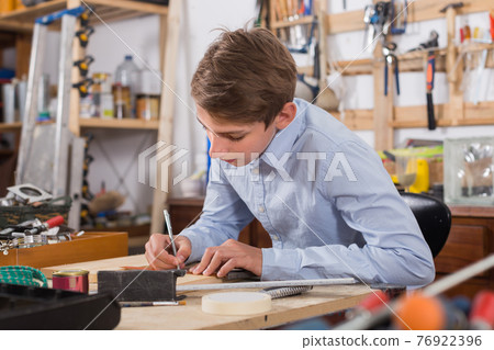 teenager smiling and working with wood in the workshop teenager smiling and working with wood in the workshop 76922396