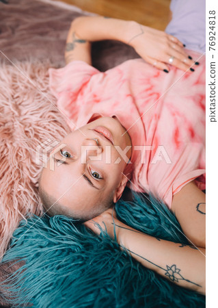 Woman with septum at her nose laying at the bed at home while having relaxed mood Woman with septum at her nose laying at the bed at home while having relaxed mood 76924818